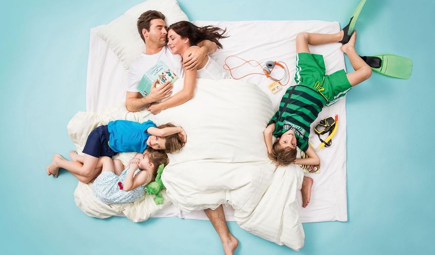 Familie entspannt im Bett mit Mama, Papa, Kindern